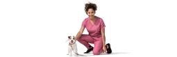 Una mujer veterinaria se hinca junto a un perro.